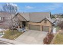 Aerial view of a brick home with a two-car garage and a covered front porch with a blue sky at 7262 Serena Dr, Castle Pines, CO 80108