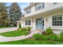 Inviting two-story home boasts a well-manicured lawn and a charming blue front door and entry at 5061 S Florence Dr, Greenwood Village, CO 80111