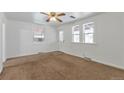 Bright living room featuring neutral paint, brown carpet, and a ceiling fan at 6900 E 66Th Ave, Commerce City, CO 80022