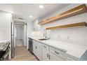 Well-lit kitchen with stainless steel appliances, quartz countertops and floating wood shelves at 2525 S Dayton Way # 1109, Denver, CO 80231