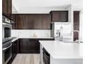 Modern kitchen with stainless steel appliances, white countertops, and dark wood cabinetry at 7811 E 123Rd Ave, Thornton, CO 80602