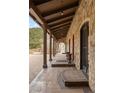 Covered stone walkway featuring timber beams and arched doorways provides elegant access to the home at 1042 Country Club Estates Dr, Castle Rock, CO 80108