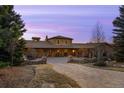 Majestic stone estate featuring an arched entryway and grand facade set against a colorful evening sky at 1042 Country Club Estates Dr, Castle Rock, CO 80108