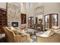 Inviting living room featuring a soaring stone fireplace, high ceilings, and abundant natural light at 1042 Country Club Estates Dr, Castle Rock, CO 80108
