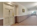 Hallway with framed art on walls leads to the front door, with decorative door hardware at 13850 E Marina Dr # 506, Aurora, CO 80014