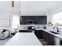 This is a modern kitchen featuring dark cabinets, stainless steel appliances, white countertops, and pendant lighting at 11914 W 57Th Dr, Arvada, CO 80002