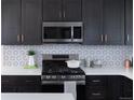 This kitchen offers dark cabinets with gold hardware, stainless steel appliances, and a white countertop at 11914 W 57Th Dr, Arvada, CO 80002