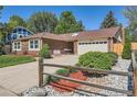 Charming brick home featuring a well-manicured lawn and a two-car garage and mature landscaping at 2093 S Holland St, Lakewood, CO 80227