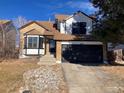 Two-story home with brick and white siding, a black garage door, and a rock garden at 20971 E 42Nd Ave, Denver, CO 80249