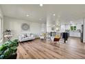 Open concept living room with hardwood floors, modern decor, and a view of the kitchen at 6749 Ingalls St, Arvada, CO 80003