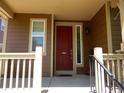 A cozy front porch featuring a vibrant red door, complemented by stylish railings and welcoming details at 7354 Benton St, Arvada, CO 80003