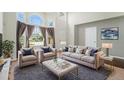 Bright living room boasts large windows, plush seating, and neutral decor for a comfortable and inviting space at 16500 Timber Cove St, Hudson, CO 80642