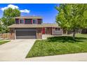 Home with a manicured lawn, mature trees, a two-car garage, and a charming red front door at 6062 S Newport St, Centennial, CO 80111