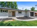 Beautiful, renovated single-story house with white brick, green shutters, updated landscaping and a stained, wood front door at 9455 W 37Th Ave, Wheat Ridge, CO 80033