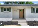 Close up on modern white brick house with black mulch, white address numbers, and stained front door at 9455 W 37Th Ave, Wheat Ridge, CO 80033