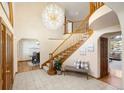 Grand foyer with a soaring ceiling, a stunning chandelier, curved staircase, and tile flooring at 2245 Ridgeview Way, Longmont, CO 80504