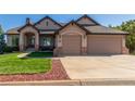 Close-up view of a home's front exterior with a two-car garage, manicured lawn, and stone accents at 228 Emerald Ct, Castle Rock, CO 80104