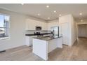 Modern kitchen with stainless steel appliances, white cabinetry, an island, and hardwood floors at 917 W Beverly St, Elizabeth, CO 80107