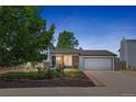Charming home at dusk with brick accents, landscaped front yard, and a two-car garage with a paved driveway at 1153 S Biscay St, Aurora, CO 80017
