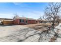 Side view of a brick home featuring a concrete driveway and partially fenced yard at 2738 Xanadu St, Aurora, CO 80011