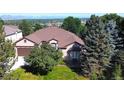 An aerial view showcases this beautiful home with lush surroundings, trees, and mountain views in the distance at 11070 Meade Ct, Westminster, CO 80031