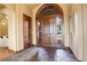Elegant foyer featuring a large arched doorway, stone flooring, and natural light at 28800 Stonecrop Trl, Conifer, CO 80433
