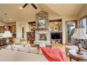 Cozy living room with a stone fireplace, wood floors, and comfortable seating at 28800 Stonecrop Trl, Conifer, CO 80433