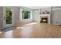 Cozy living room featuring a fireplace, hardwood floors, and natural light from the large windows at 11578 Clayton St, Thornton, CO 80233