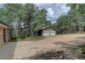 Home exterior showcasing the two-car garage, gravel driveway, stone accents, and lush surrounding trees at 28858 Richmond Hill Rd, Conifer, CO 80433