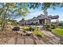 Landscaped backyard features a stone patio, outdoor seating, a grill, and lush greenery at 3080 Big Bear Dr, Sedalia, CO 80135