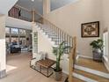 Elegant foyer featuring staircase with iron railings, light wood floors, and stylish decor at 7292 Tenby Way, Castle Pines, CO 80108