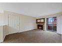 Living room with stone fireplace and sliding doors to an outdoor balcony at 4691 S Decatur St # 212, Englewood, CO 80110