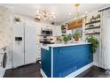 Well-lit kitchen featuring white cabinets, stainless steel appliances, and a stylish blue island at 9620 W Chatfield Ave # D, Littleton, CO 80128