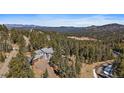 Scenic aerial view of property with a beautiful home surrounded by lush greenery and rolling hills at 6637 Berry Bush Ln, Evergreen, CO 80439