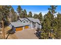 A beautiful two-story home with a three-car garage surrounded by mature trees and lush greenery at 6637 Berry Bush Ln, Evergreen, CO 80439