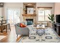 Bright living room with a stone fireplace, sliding glass doors, and hardwood floors with large patterned rug at 9150 Gale Blvd # 1, Thornton, CO 80260