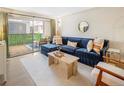 Bright living room with a plush blue sectional, neutral rug, and sliding glass doors to a patio at 2 Adams Street # 108, Denver, CO 80206