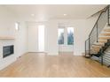 Bright, open-concept living room with hardwood floors, modern fireplace, and stylish staircase at 2685 S Acoma St, Denver, CO 80223