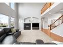Spacious living room featuring high ceilings, fireplace, staircase, and a comfortable leather sectional at 23427 Song Bird Hills Pl, Parker, CO 80138