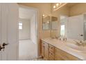 Bright bathroom with double vanity, tile floors, and view into bedroom with neutral carpet at 1864 Malibu Ct, Fort Lupton, CO 80621