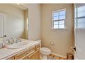 Bright bathroom with a white tile countertop, wood cabinets, and a window with natural light at 1864 Malibu Ct, Fort Lupton, CO 80621