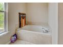 Inviting soaking tub area with tile surround, a window, and a Harley-Davidson towel for decor at 1864 Malibu Ct, Fort Lupton, CO 80621