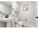 Clean powder room offering a pedestal sink, modern fixtures, a framed art print, and essential storage at 1071 Oak Cir, Lakewood, CO 80215
