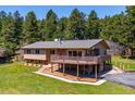 Charming home featuring a large wooden deck, stone accents, and an attached garage, all surrounded by a green lawn at 8045 S Wagon Wheel Rd, Morrison, CO 80465