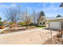 Inviting home featuring a detached garage, landscaped lawn, and paved driveway at 21 Snowmass Pl, Longmont, CO 80504