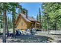 Exterior of cozy cabin featuring a patio with chairs and grill amidst tall trees at 29 Gregory Cir, Breckenridge, CO 80424
