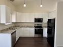 Modern kitchen with white cabinets, granite countertops, and stainless steel appliances at 6610 Monaco Way, Brighton, CO 80602