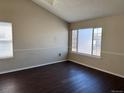 Bright living room features a large window, neutral paint and wood-look floors at 6610 Monaco Way, Brighton, CO 80602