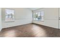 Bright living room with wood floors and two windows providing natural light at 6610 Monaco Way, Brighton, CO 80602