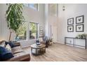 Spacious living room with two-story ceilings, natural light, wood flooring, and cozy seating arrangements at 6039 S Ukraine Cir, Aurora, CO 80015